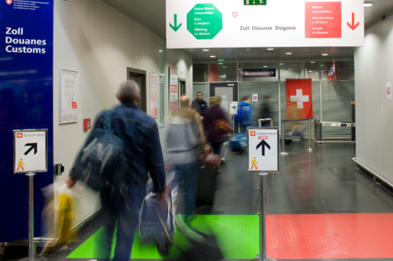 I viaggiatori passano attraverso il passaggio rosso / verde in aeroporto